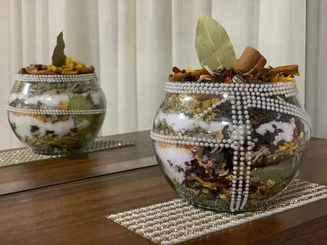 Dois amuletos energéticos em vasos de vidro com camadas de ervas, sal e folhas de louro