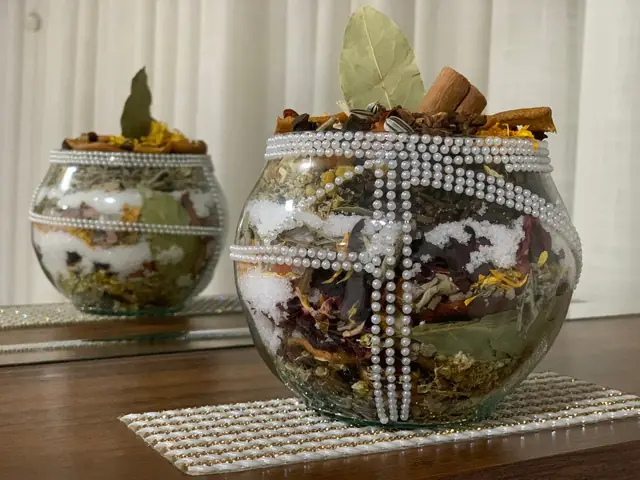 Dois amuletos energéticos em vasos de vidro com ervas, laranja desidratada e flores secas